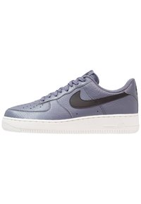 Sneakers Nike Air Force 1 w jasnofioletowej skórze, z czarnym swooshem, perforowanym noskiem i białą gumową podeszwą.