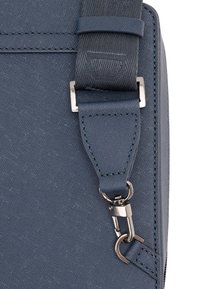 Dunkelblaue Schultertasche aus strukturiertem Stoff, mit einem Metallclip und verstellbarem Tragegurt sowie dezenten Stichdetails.