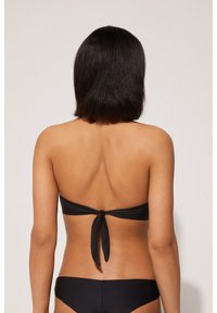 Czarny komplet bikini składa się z biustonosza bez ramiączek z zapięciem na plecach oraz pasujących majtek. Gładka faktura, minimalistyczny design.