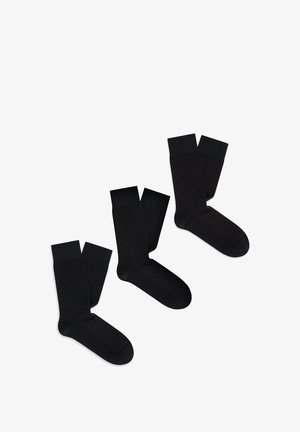 Czarne skarpetki z teksturowanym wzorem z małymi kropkami, wykonane z miękkiego materiału. Każda para ma gładki czarny ściągacz i wzmocniony palec.