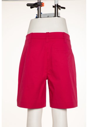 Lyserøde shorts lavet af stof med en glat tekstur. Har forkørsler, bælteløkker og en enkelt baglomme.