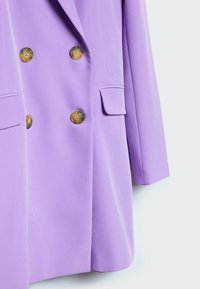 Blazer lilas croisé à double boutonnage avec quatre grands boutons en écaille de tortue et deux poches à rabat, présenté de la taille à la manche.