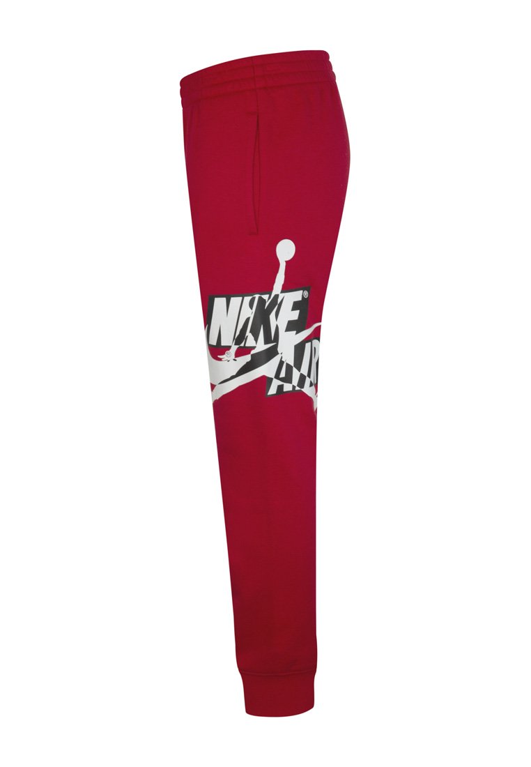 Pantalones de chándal rojos con pierna ajustada, que presentan un gran gráfico blanco de "NIKE AIR" y una silueta saltando. Hechos de una tela suave, con cinturilla elástica.