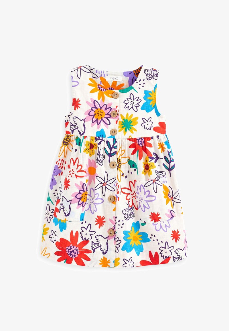 Robe blanche sans manches avec des imprimés colorés de fleurs et d'oiseaux, boutons en bois sur le devant et taille froncée avec une poche à l'avant.