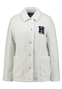 Witte fleecejack met een kraag, drukknopen, twee voorzakken en een blauw geborduurd "H"-logo op de borst. Getextureerde stof.