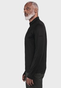 Langarmhemd in Schwarz mit hohem Kragen und figurbetontem Schnitt. Das Material wirkt glatt und beinhaltet ein Logodetail auf dem Ärmel.