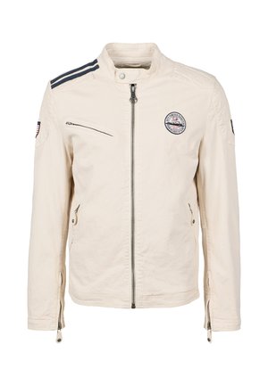 Veste beige avec col montant, fermeture éclair à l'avant, poches latérales et rayures bleu marine sur les épaules. Comprend une écusson sur la poitrine.