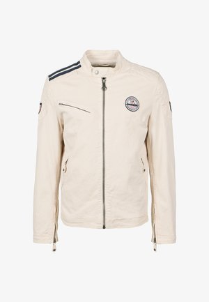 Veste beige avec col montant, fermeture éclair à l'avant, poches latérales et rayures bleu marine sur les épaules. Comprend une écusson sur la poitrine.