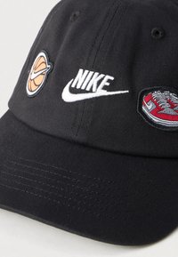 Μαύρο καπέλο μπέιζμπολ από βαμβάκι, με κεντημένο το λογότυπο της Nike, σχέδια μπάσκετ και αθλητικών παπουτσιών μπροστά. Υφή με ανάγλυφη επιφάνεια, δομημένο σχήμα.