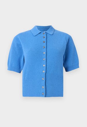 Cardigan bleu en tricot à manches courtes avec col et rangée verticale de boutons marron sur fond uni.