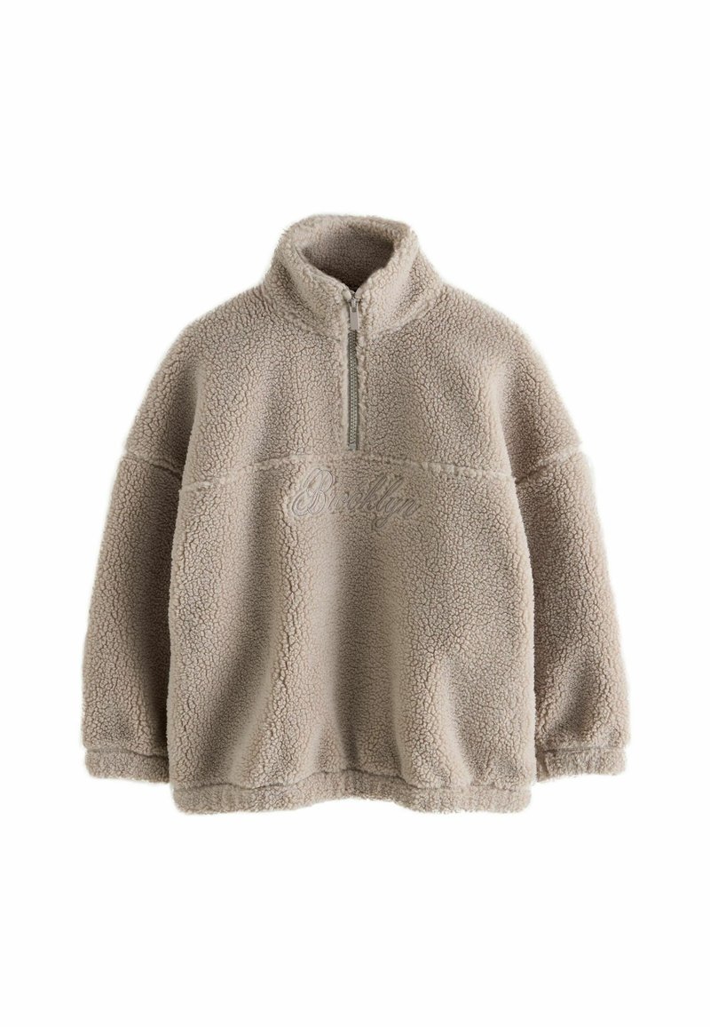 Pull beige en polaire sherpa avec demi-fermeture éclair devant et col haut, avec un texte brodé subtil sur la poitrine.