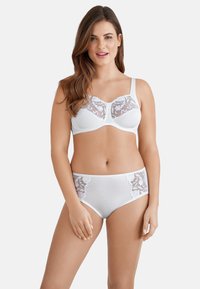 Witte lingerieset met een beha met doorschijnende bloemenkant en bijpassende hoogsluitende slipjes met kantaccenten aan de zijkanten.