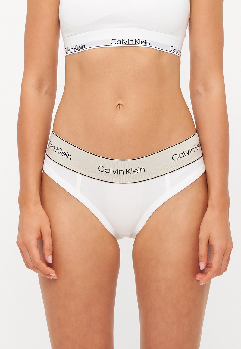 Calvin Klein witte slips met een beige elastische tailleband met logo-accenten. Glad materiaal met een klassieke snit en minimale ontwerpelementen.