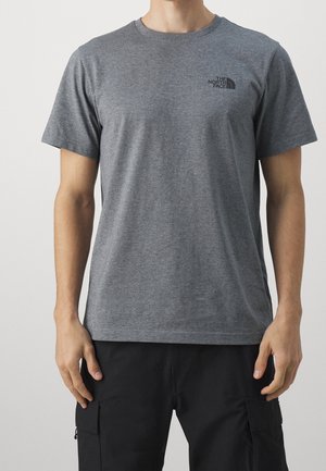 Mann trägt ein graues T-Shirt mit kurzen Ärmeln und Rundhalsausschnitt mit dem Logo "The North Face" auf der oberen linken Brustseite und schwarzen Cargohosen.