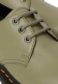 Scarpa di pelle verde con finitura testurizzata, punta rotonda e suola nera a contrasto. Presenta occhielli in metallo e lacci testurizzati.