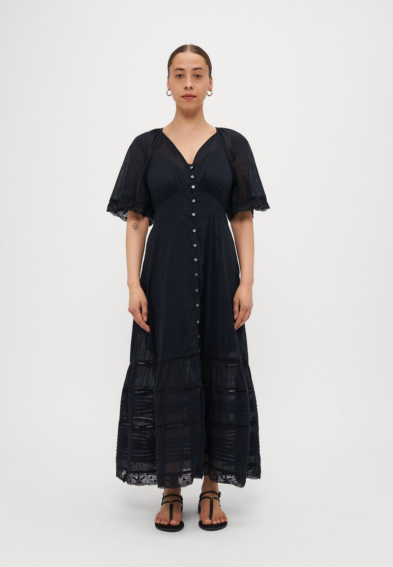Robe maxi noire avec des manches courtes et transparentes, devant à boutons et accents en dentelle au niveau de l'ourlet. Fabriquée en tissu léger avec un design à volants.