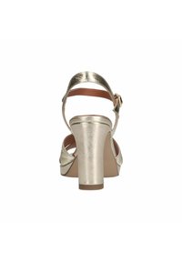 Gouden metalen haksandalen met een brede blokhak, open achterkant, verstelbare enkelband en een gladde textuurafwerking.