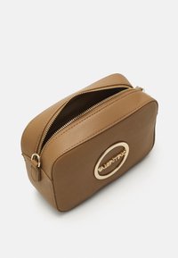 Pochette in pelle marrone con hardware dorato, forma rettangolare, chiusura con zip e logo impressa sulla parte anteriore. Texture liscia e design minimale.