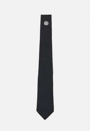 Corbata de gala hecha de tela suave, presenta un extremo puntiagudo y un acento circular metálico cerca de la punta. Diseño simple y sólido sin patrones.