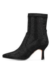 Botín negro con punta afilada, fabricado en ante perforado. Presenta un tacón delgado y un puño texturizado para una silueta elegante.