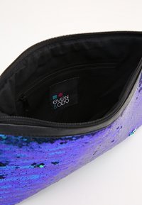 Lila paljetterad clutch med metallisk lyster, svart innerfoder och dragkedjestängning. Innehåller en etikett med "even & odd."