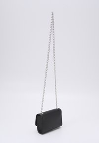 Sac en cuir noir en bandoulière avec une surface texturée, doté d'une chaîne en acier argenté. Forme rectangulaire compacte, design minimaliste.