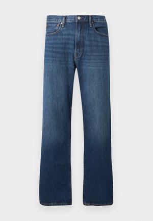 Rovno-strihané modré denimové rifle s klasickým dizajnom s piatimi vreckami a zapínaním na gombík na jednoduchom svetlom pozadí.