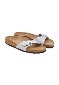 Chanclas con una tira de purpurina plateada y hebilla metálica ajustable, plantilla de corcho y una suela de goma negra texturizada.