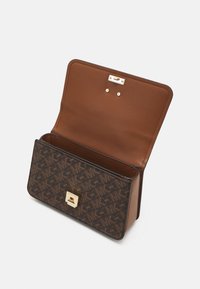 Ruda odinė rankinė su monogramų raštu, auksinėmis detalėmis ir užsegimu. Yra tekstūruota, kontrastinga vidinė dalis.