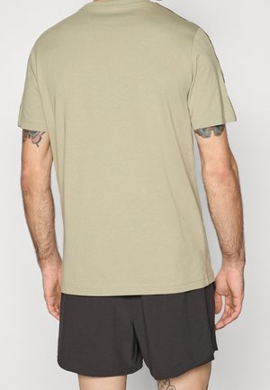 Kortærmet t-shirt i olivengrøn blød bomuldsblanding, med et enkelt design og en lige kant, kombineret med sorte shorts.