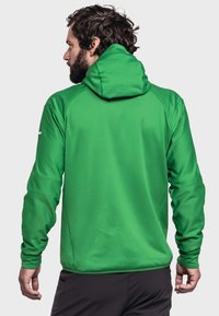 Grüne Kapuzenjacke aus strukturiertem Stoff, mit tailliertem Schnitt und langen Ärmeln. Die Rückansicht zeigt eine nahtlose Verarbeitung und Details zur Kapuze.