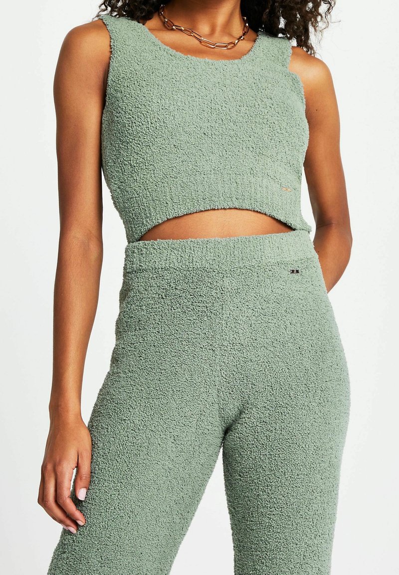 Top cropped verde in un materiale texturizzato e fuzzy, abbinato a pantaloni a vita alta coordinati, entrambi con una finitura morbida e accogliente.