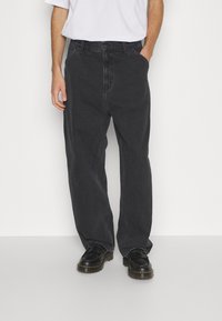Dunkelgraue Jeans mit lockerer Passform, klassischer 5-Pocket-Design und umgeschlagenen Säumen, kombiniert mit schwarzen Schuhen.
