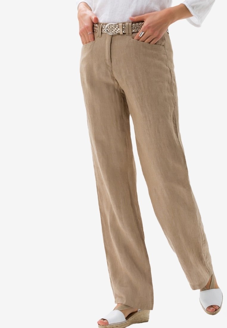 Ljust bruna linnebyxor med rak passform, med sidofickor och ett flätat silverfärgat bälte, bärs med vita espadriller.