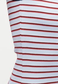 Κοντινό πλάνο υφάσματος ανοιχτού γαλάζιου με ριμπ ύφανση και ομοιόμορφες οριζόντιες κόκκινες και σκούρες καφέ ρίγες σε εφαρμοστό ένδυμα.