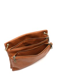 Sac à main en cuir marron avec deux compartiments zippés, intérieur clair, matériel en laiton et texture douce. Forme incurvée et design minimaliste.