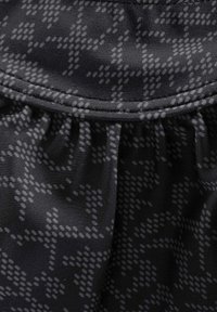 Una tela texturizada en tonos de negro y gris presenta un patrón geométrico. El material es suave, con un acabado ligeramente brillante y bordes fruncidos.