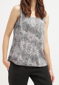 Tílko s černobílým paisley vzorem, výstřihem do oblouku, bez rukávů a volným střihem. Měkká látka s hladkým povrchem.