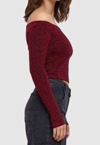 Burgundy off-the-shoulder crop top dengan lengan panjang, terbuat dari bahan berkilau, desain pas badan, tekstur halus, dan potongan crop.