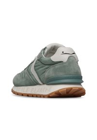Sneaker verde in suede con accenti bianchi, forma arrotondata, tomaia testurizzata e suola in gomma marrone chiaro con branding "VOILE BLANCHE".