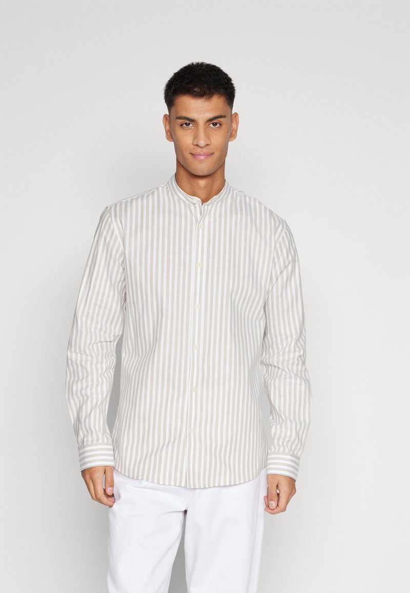 Camisa de manga larga en color beige claro con rayas verticales blancas, cuello bandeja y cierre de botones. La tela parece suave con una ligera textura.