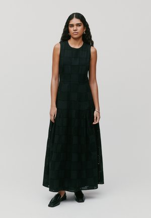 Zwarte maxi-jurk met een mouwloos ontwerp, geruite patroon met oogjes snedes en geplooide textuur rondom de taille.