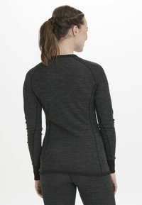 Aansluitend zwart sportshirt met lange mouwen van textuurstof, raglanmouwen en contrasterende naden aan de achterkant.