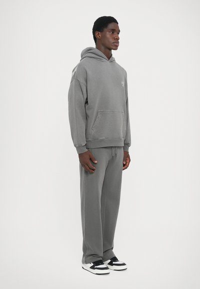 Gray hooded sweatshirt with a front pocket, paired with matching gray sweatpants. Features a relaxed fit and minimal branding.