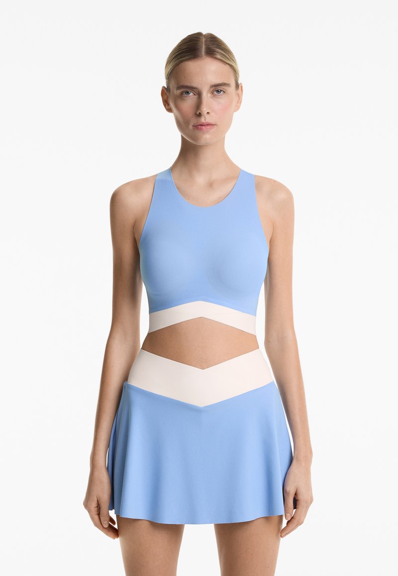 Light blue athletic outfit featuring a fitted top with a round neckline and a flared skirt with cream accents at the waist for contrast.
