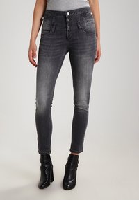 Černé skinny džíny ve vybledlém odstínu, s vysokým pasem, vícezdrojovým zapínáním a předními kapsami. Hladká denimová textura.