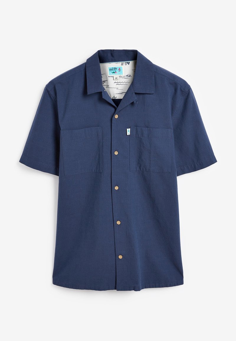 Chemise bleu marine à manches courtes avec col, comportant deux poches avant et des boutons en bois, fabriquée en tissu texturé.