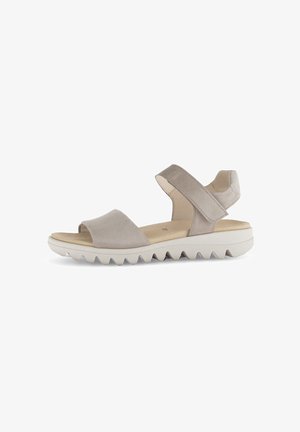 Beige suede sandals with cross-strap design, open toe, and adjustable ankle strap. Thick white sole with zigzag tread pattern.