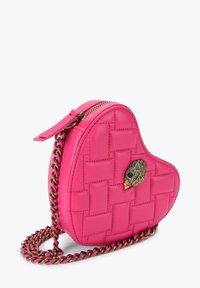 Hartvormige, roze, gewatteerde handtas met gouden vogel-embleem en bijpassende kettingriem op witte achtergrond.