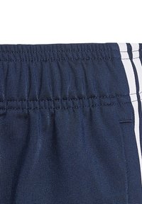 Námornícke športové šortky s elastickým pásom, s bielymi bočnými pruhmi a štruktúrovanou tkaninou pre trvanlivosť a pohodlie.